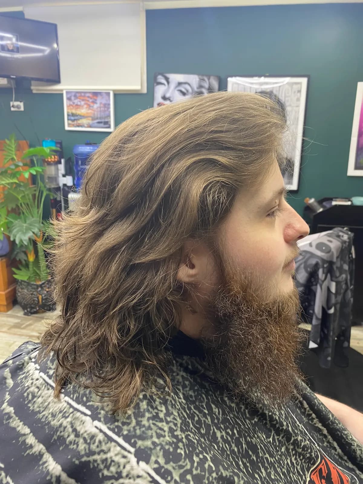 Barbershop client with long wavy hair and a full beard styled at Bear Cave Barbershop