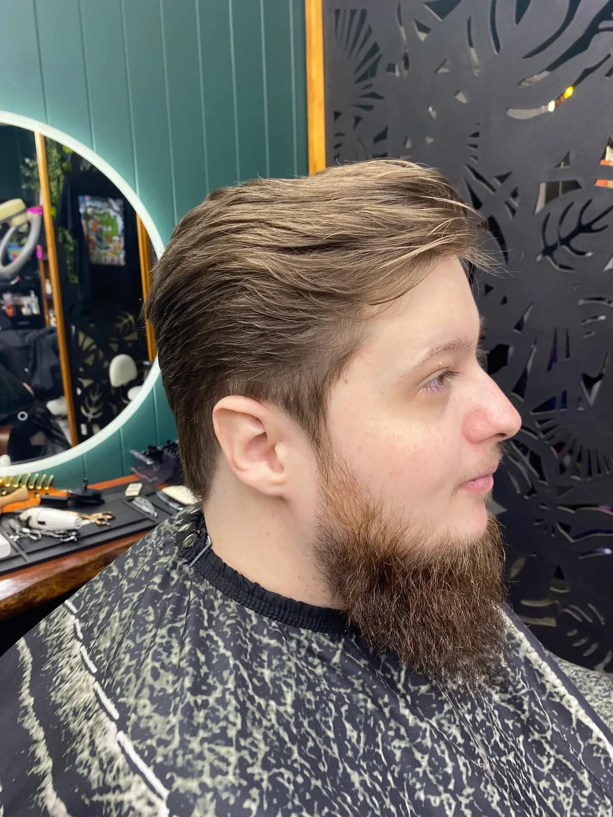 Side profile of a short back and sides haircut with a swept-back top at Bear Cave Barbershop